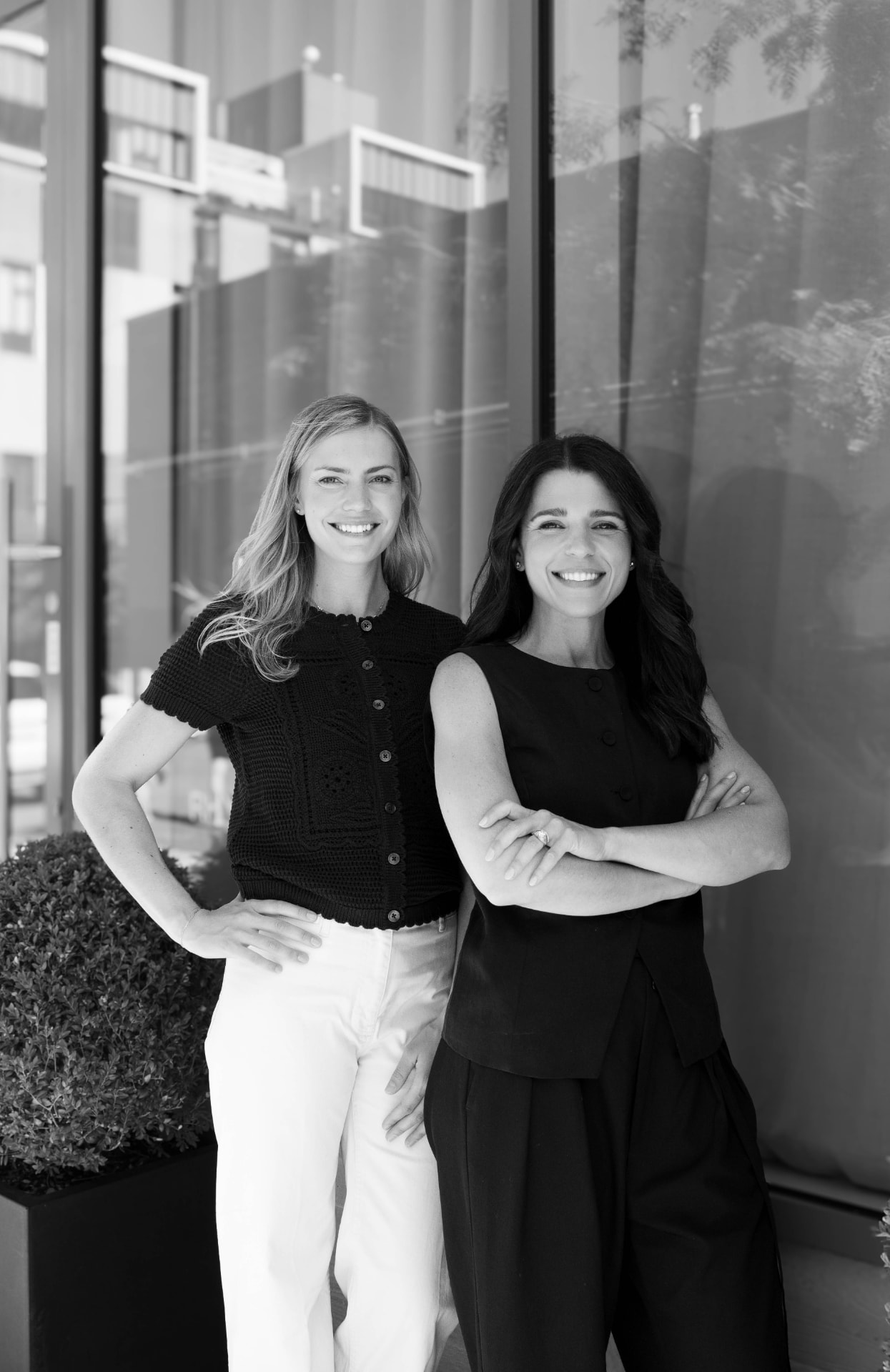 The two hosts of Caring Through It standing together outside the studio